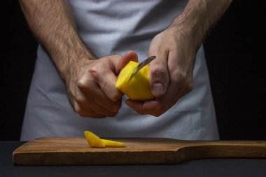 Siyah arka planda patatesler. Aşçı patatesleri bıçakla keser. Erkek eli siyah arka planda patates kesiyor.