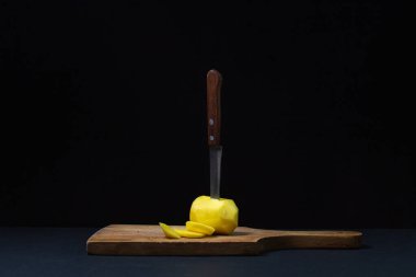 Siyah arka planda patatesler. Siyah arka planda soyulmuş patates. Bıçak patatesleri keser.