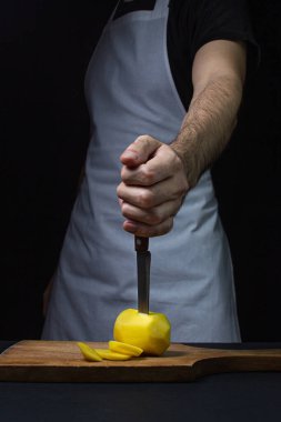 Siyah arka planda patatesler. Siyah arka planda patatesli bıçak. Bıçak tutan el.