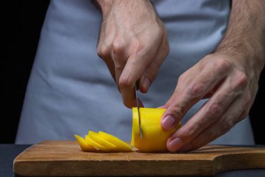 Siyah arka planda patatesler. Aşçı patatesleri bıçakla keser. Erkek eli siyah arka planda patates kesiyor.