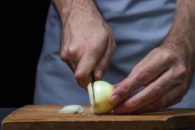 Koyu arkaplanda soğan. Aşçı siyah arka planda soğanı keser. Soğanları dilimliyorum.