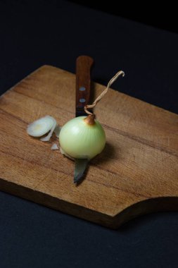 Koyu arkaplanda soğan. Soğan dilimliyorum. Bir bıçak tahtadan soğan keser..