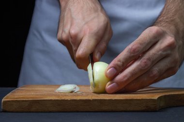 Koyu arkaplanda soğan. Aşçı siyah arka planda soğanı keser. Soğanları dilimliyorum.