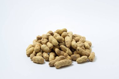 Beyaz arka planda yer fıstıkları. Küçük bir fıstık yığını. Kabuklu fıstıklar