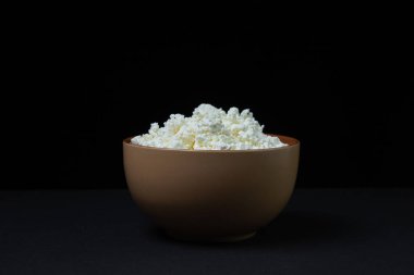 Siyah arka planda kaymak. Koyu bir zeminde ev yapımı süzme peynir. Süt ürünü