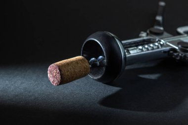 Arka planda tirbuşon var. Siyah arka planda tirbuşonda şarap mantarı. Çelik tirbuşon.