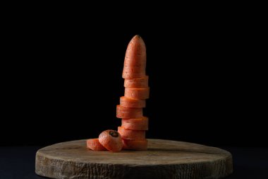 Koyu arkaplanda havuçlar. Siyah arka planda tahta bir tahtada dilimlenmiş havuçlar. Sağlıklı yemek.