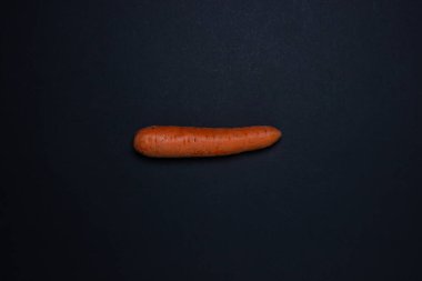 Koyu arkaplanda havuçlar. Çerçevenin ortasında bir havuç. Siyah arka planda bütün havuçlar