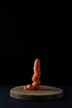 Koyu arkaplanda havuçlar. Siyah arka planda tahta bir tahtada dilimlenmiş havuçlar. Sağlıklı yemek.