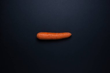 Koyu arkaplanda havuçlar. Çerçevenin ortasında bir havuç. Siyah arka planda bütün havuçlar