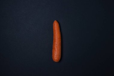 Koyu arkaplanda havuçlar. Çerçevenin ortasında bir havuç. Siyah arka planda bütün havuçlar