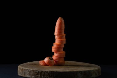 Koyu arkaplanda havuçlar. Siyah arka planda tahta bir tahtada dilimlenmiş havuçlar. Sağlıklı yemek.