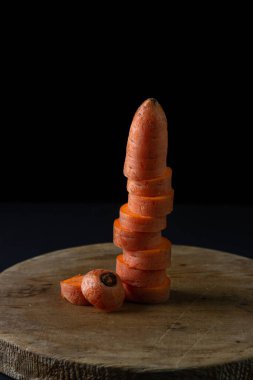 Koyu arkaplanda havuçlar. Siyah arka planda tahta bir tahtada dilimlenmiş havuçlar. Sağlıklı yemek.