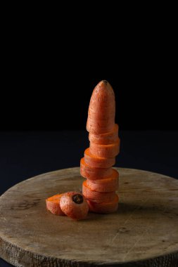 Koyu arkaplanda havuçlar. Siyah arka planda tahta bir tahtada dilimlenmiş havuçlar. Sağlıklı yemek.