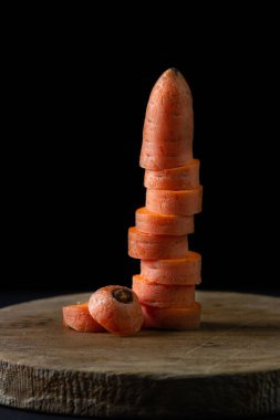 Koyu arkaplanda havuçlar. Siyah arka planda tahta bir tahtada dilimlenmiş havuçlar. Sağlıklı yemek.