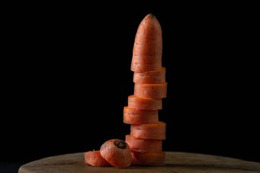 Koyu arkaplanda havuçlar. Siyah arka planda tahta bir tahtada dilimlenmiş havuçlar. Sağlıklı yemek.