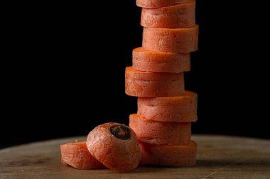 Koyu arkaplanda havuçlar. Siyah arka planda tahta bir tahtada dilimlenmiş havuçlar. Sağlıklı yemek.