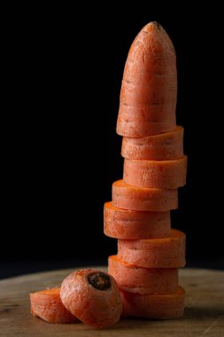 Koyu arkaplanda havuçlar. Siyah arka planda tahta bir tahtada dilimlenmiş havuçlar. Sağlıklı yemek.