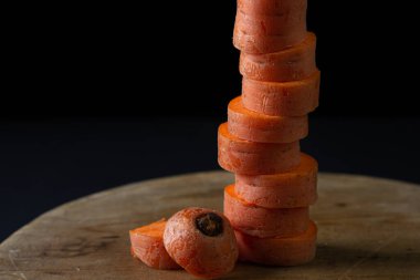 Koyu arkaplanda havuçlar. Siyah arka planda tahta bir tahtada dilimlenmiş havuçlar. Sağlıklı yemek.