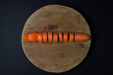 Koyu arkaplanda havuçlar. Siyah arka planda tahta bir tahtada dilimlenmiş havuçlar. Sağlıklı yemek.
