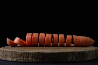 Koyu arkaplanda havuçlar. Siyah arka planda tahta bir tahtada dilimlenmiş havuçlar. Sağlıklı yemek.