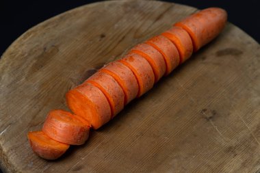 Koyu arkaplanda havuçlar. Siyah arka planda tahta bir tahtada dilimlenmiş havuçlar. Sağlıklı yemek.