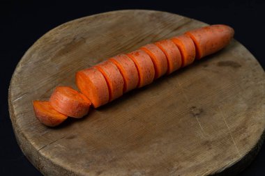 Koyu arkaplanda havuçlar. Siyah arka planda tahta bir tahtada dilimlenmiş havuçlar. Sağlıklı yemek.