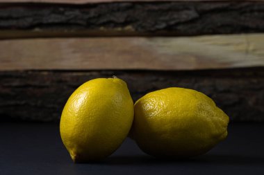 Koyu bir arka planda limon. Ahşap arka planda iki limon. Limonun yaratıcı fotoğrafı.