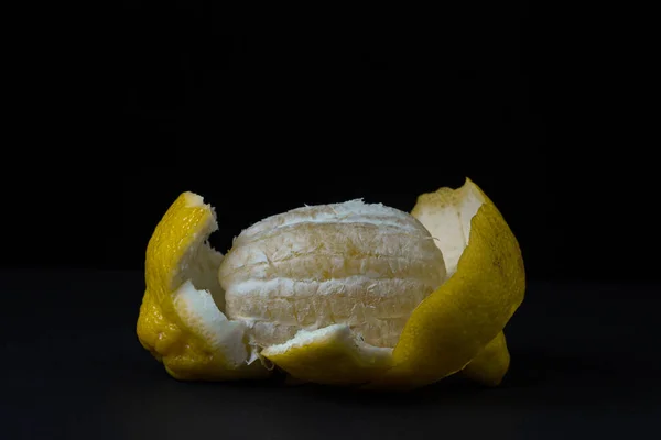 Koyu bir arka planda limon. Kabuğu soyulmuş bir limon siyah bir arkaplanda duruyor. Limonun yaratıcı fotoğrafı.