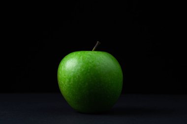 Siyah arka planda yeşil elma. Siyah arka planda kesilmiş yeşil bir elma. Sağlıklı yemek.