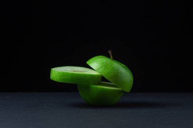Siyah arka planda yeşil elma. Siyah arka planda kesilmiş yeşil bir elma. Sağlıklı yemek.