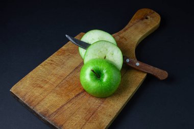 Siyah arka planda yeşil elma. Siyah arka planda kesme tahtasında kesilmiş yeşil bir elma. Sağlıklı yemek.