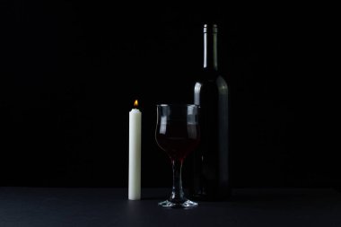 Karanlık bir arka planda şarap ve mum. Siyah arka planda kırmızı şarabın yaratıcı bir fotoğrafı. Şarap ve mum dumanı