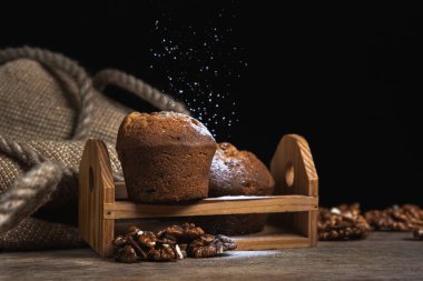 Kekler koyu arkaplana pudra şekeri serpiştirilmiş. Siyah arka planda şekerleme. Cevizli kek.