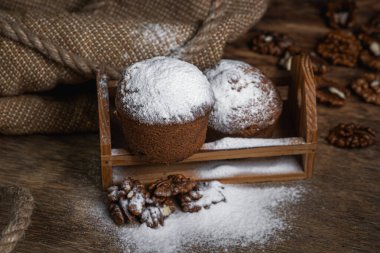 Kekler koyu arkaplana pudra şekeri serpiştirilmiş. Siyah arka planda şekerleme. Cevizli kek.