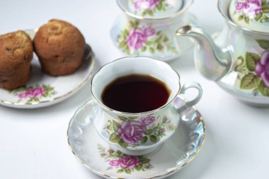 Beyaz masa örtüsü üzerinde bir fincan çay. Kekli çay. Hafif kahvaltı. Çiçekli beyaz çay seti.