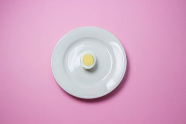 Haşlanmış yumurta tabakta ikiye bölünmüş. Sağlıklı kahvaltı. Pembe arka planda haşlanmış yumurta.