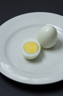 Haşlanmış yumurta tabakta ikiye bölünmüş. Sağlıklı kahvaltı. Siyah arkaplanda haşlanmış yumurta.