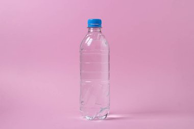 Pembe arka planda su şişesi. Plastik şişe ve su. Temiz içme suyu.