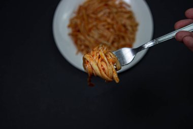 Arka planda domates soslu spagetti. Siyah arka planda spagetti çatalı. İtalyan yemeği. Lezzetli yemek.