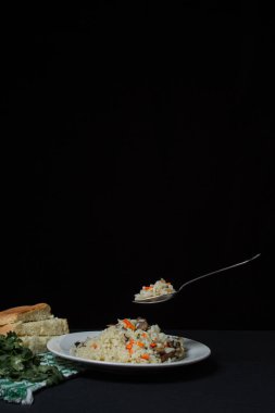 Siyah arka planda Pilaf. Tabağın üzerinde bir kaşık pilav. Karanlık arka planda yaratıcı yiyecek fotoğrafçılığı