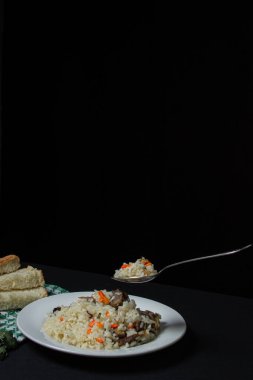 Siyah arka planda Pilaf. Tabağın üzerinde bir kaşık pilav. Karanlık arka planda yaratıcı yiyecek fotoğrafçılığı