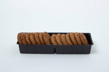 Beyaz arka planda plastik bir kapta yulaflı kurabiyeler. Diyet yemek. Hafif kahvaltı.