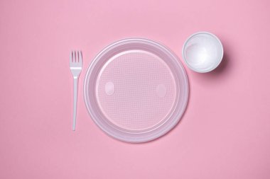 Pembe arka planda plastik tabaklar. Tek kullanımlık sofra takımı. Plastik ürünler.