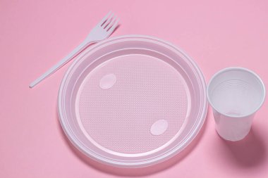 Pembe arka planda plastik tabaklar. Tek kullanımlık sofra takımı. Plastik ürünler.