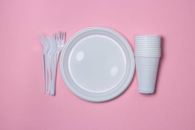 Pembe arka planda plastik tabaklar. Tek kullanımlık sofra takımı. Plastik ürünler.