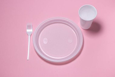 Pembe arka planda plastik tabaklar. Tek kullanımlık sofra takımı. Plastik ürünler.
