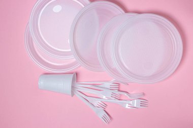 Pembe arka planda plastik tabaklar. Tek kullanımlık sofra takımı. Plastik ürünler.