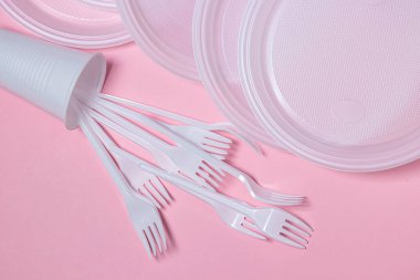 Pembe arka planda plastik tabaklar. Tek kullanımlık sofra takımı. Plastik ürünler.