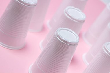 Pembe arka planda plastik gözlük. Tek kullanımlık sofra takımı. Plastik ürünler.